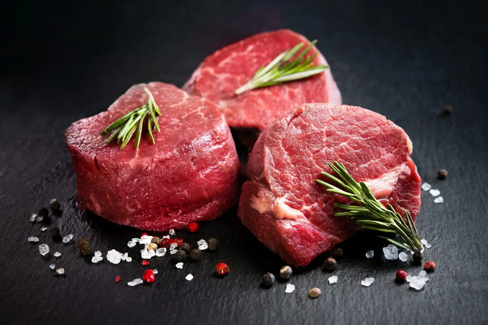 Raw beef steaks with herbs and spices.